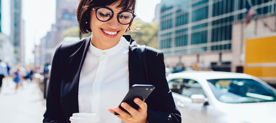 Woman working in municipal and government industry looking at her mobile phone while walking so she can manage her GIS